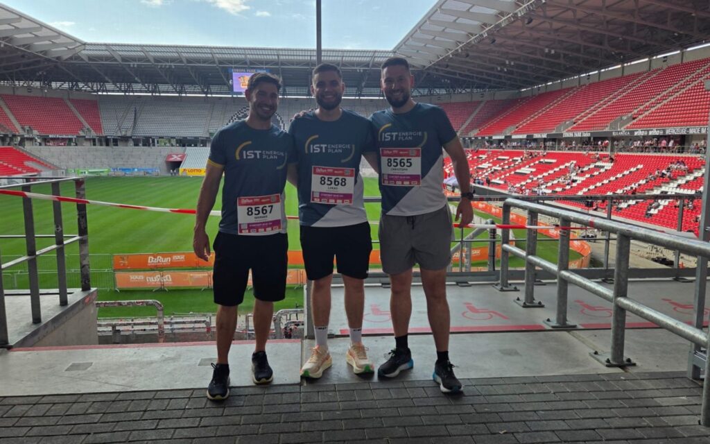 Auf dem Bild sieht man drei unserer Mitarbeiter im Firmen-Trikot im Stadion, wo das Ziel des B2B-Runs 2026 war.