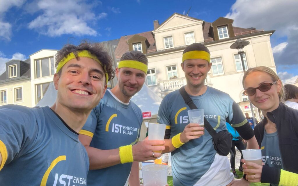 Auf dem Bild sieht man drei IST Mitarbeiter sowie eine Frau. Alle tragen die IST-Laufshirts und leuchtend gelbe Schweißbänder.